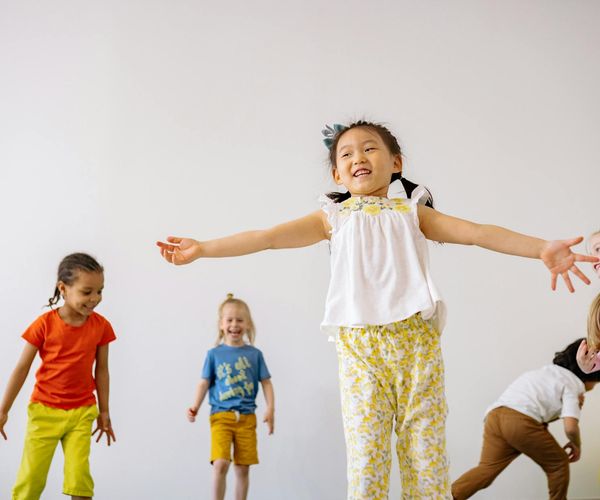 Group of happy children in a bright room doing playful yoga poses.